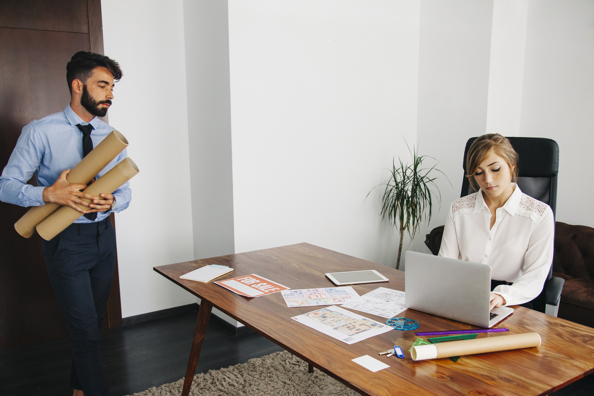 Agents immobiliers dans leur agence avec un panneau à vendre