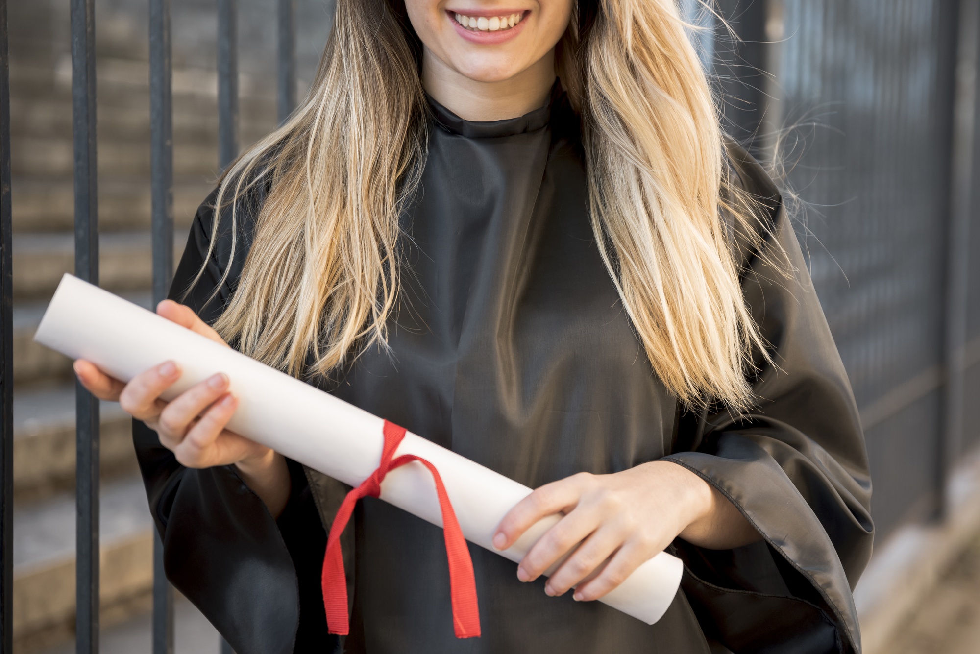 Jeune diplômée souriante tenant son diplôme enroulé