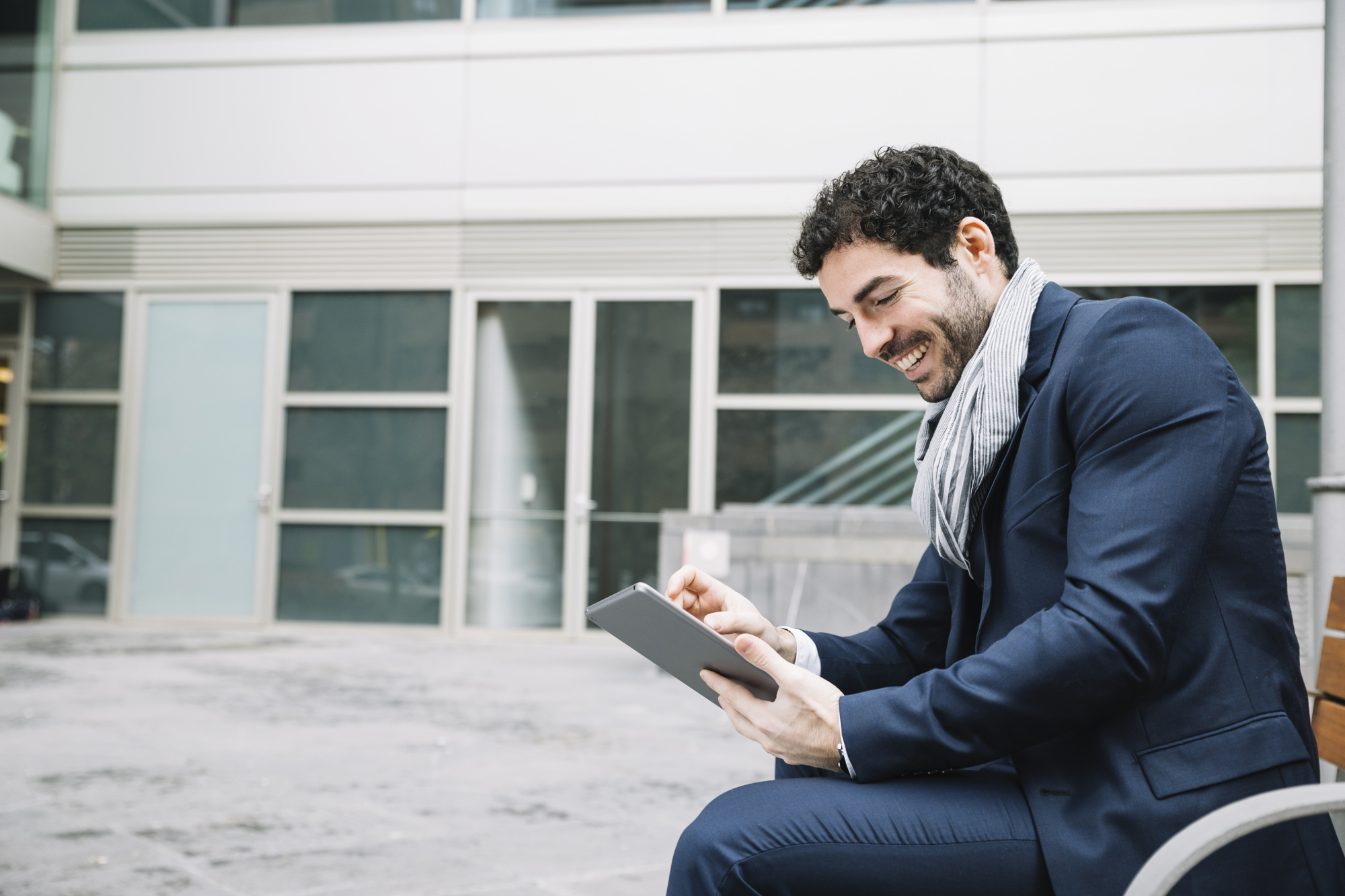 Homme d'affaires souriant consultant une tablette en extérieur