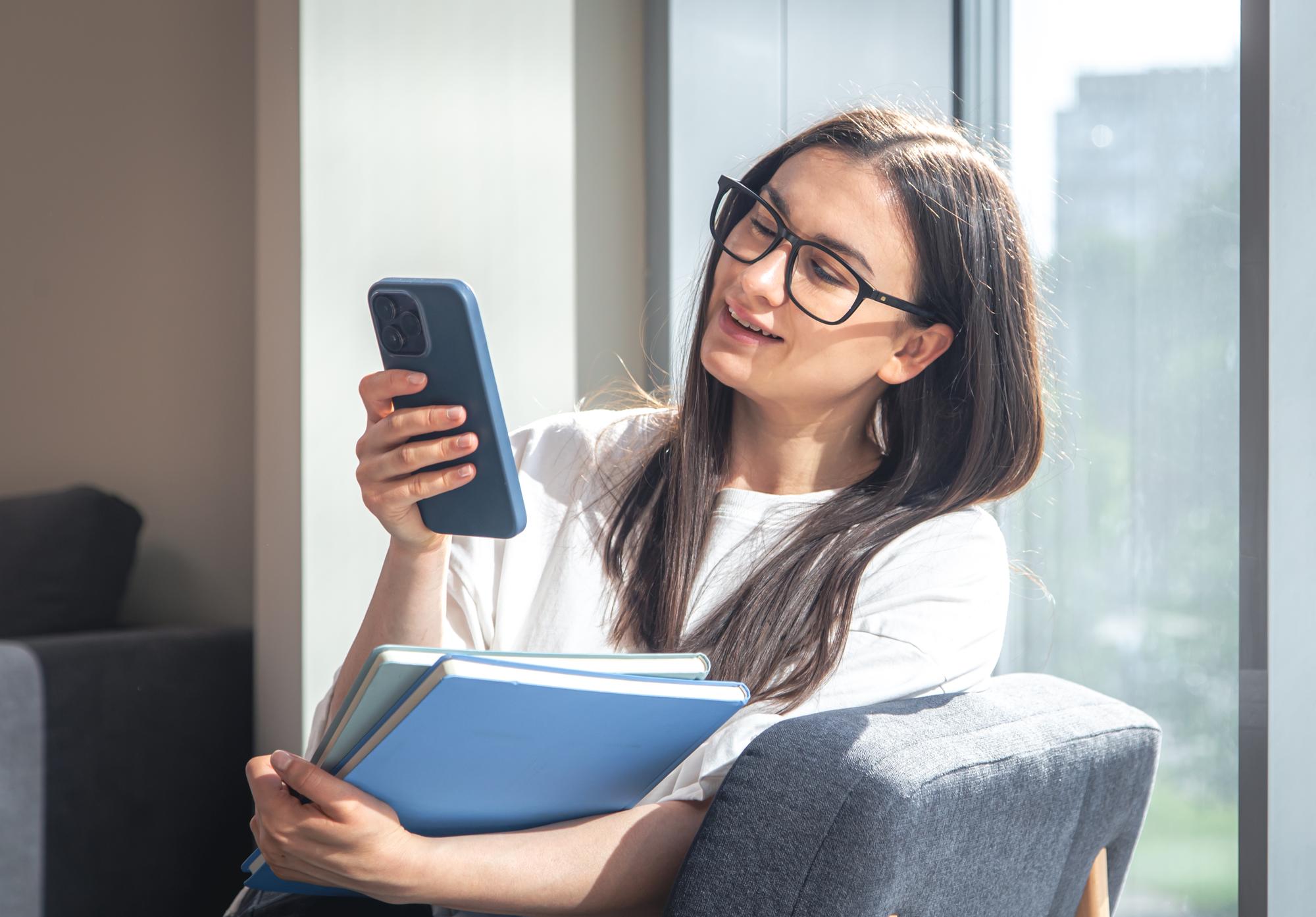 Professionnel concentré consultant son smartphone accompagné de carnets de notes