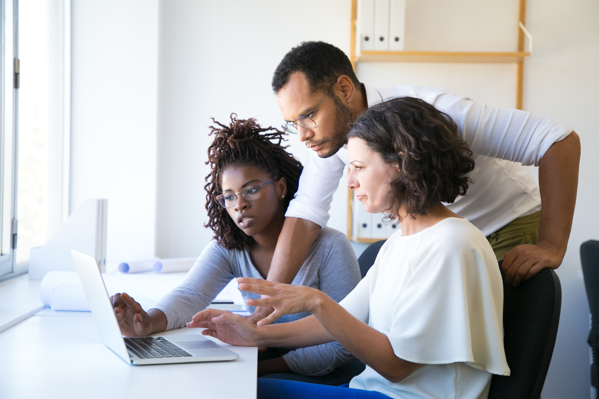 Trois collègues formant un nouvel employé devant un ordinateur portable
