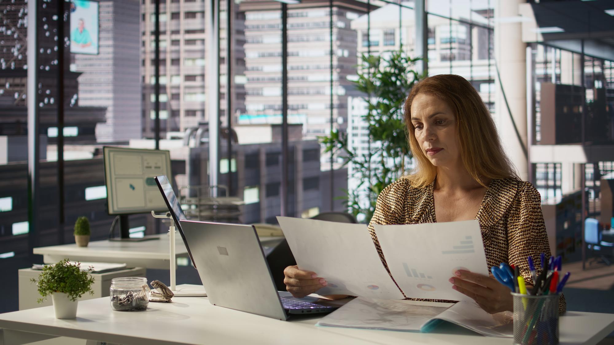 Femme d'affaires étudiant des documents et graphiques au bureau