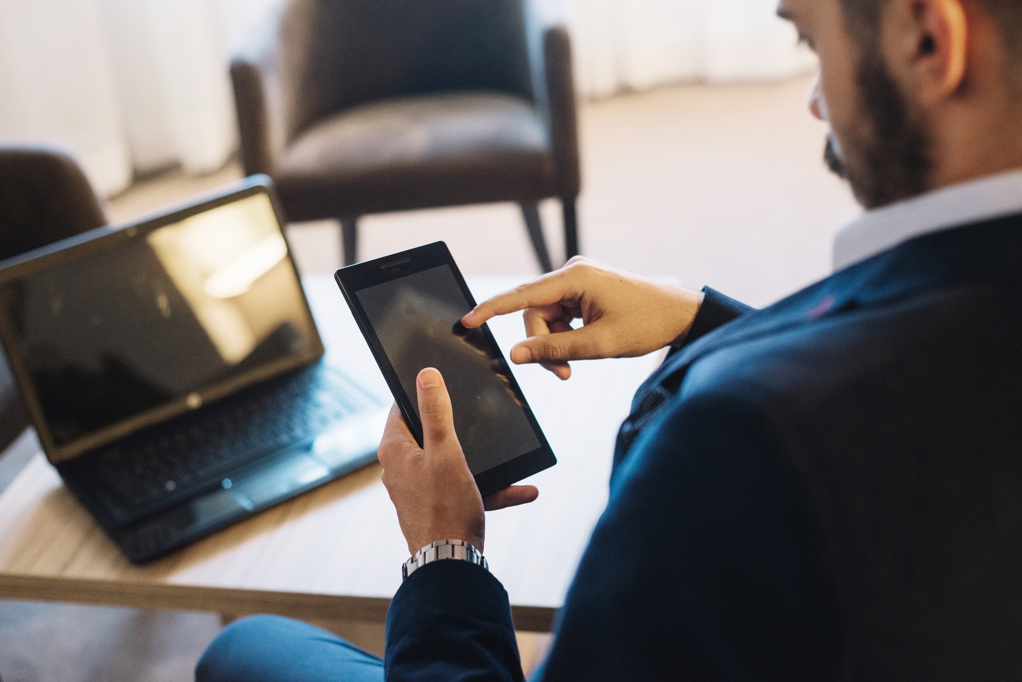 Professionnel consultant une tablette près d'un ordinateur portable dans un salon lumineux